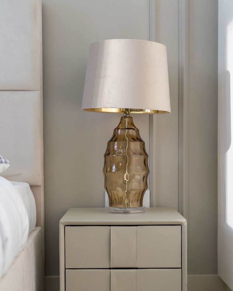 Feed post: a lamp with a glass base on a bedside table