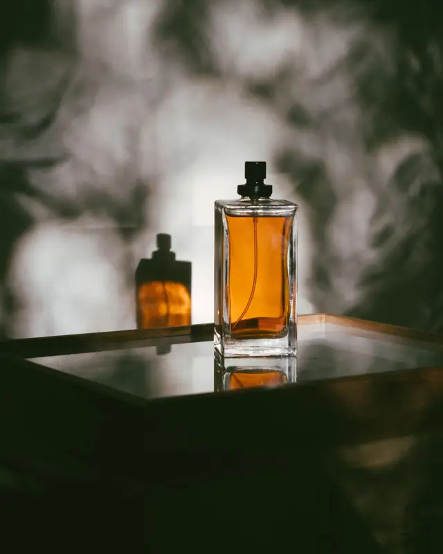 Amber perfume bottles on a mirrored tray in smoke