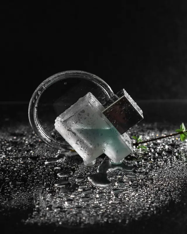 A frosted perfume bottle beaded with water on black stone