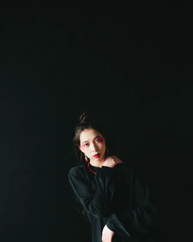 A woman in black against a black backdrop
