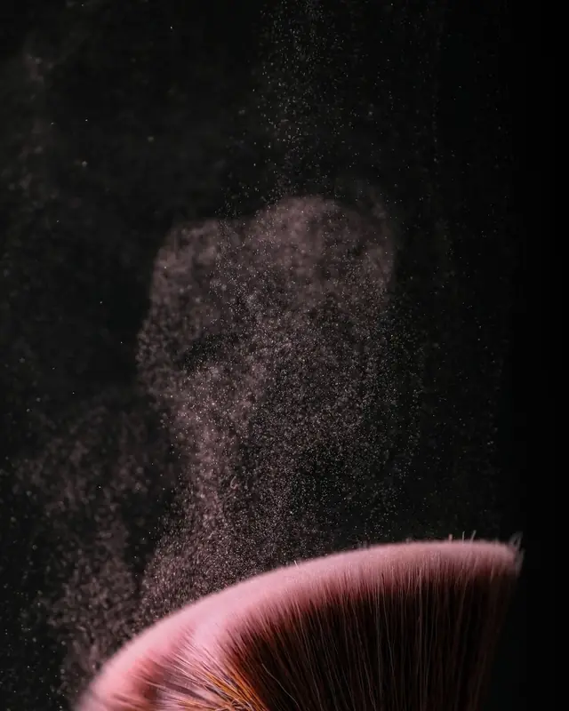 Two make-up brushes in a cloud of pink powder