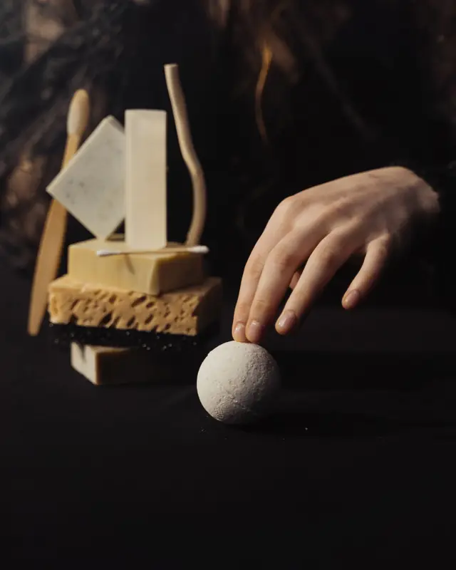 A hand arranging soap bars and a stone sphere