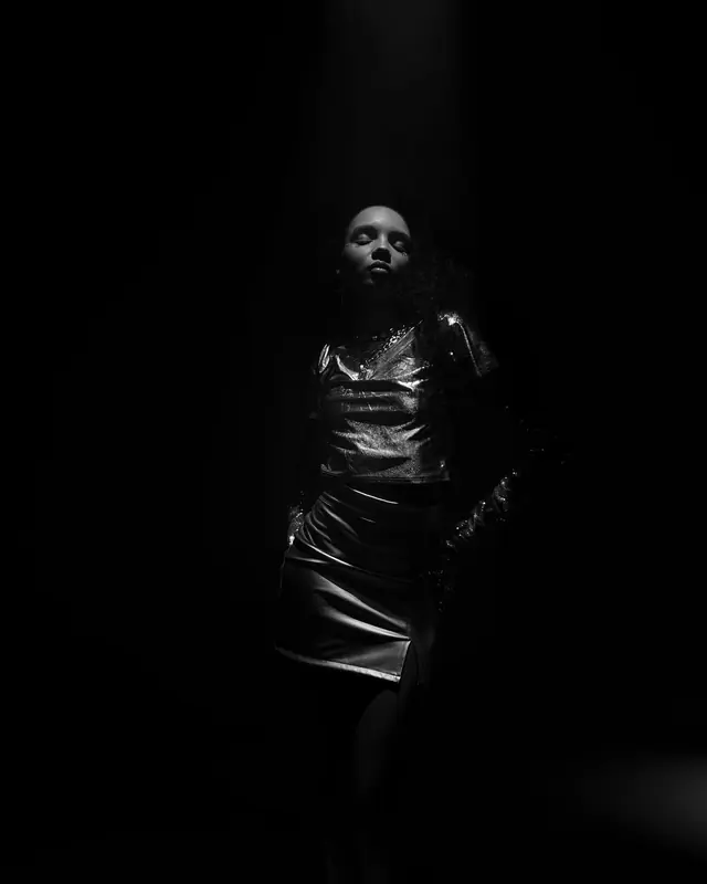 A figure in black under a single spotlight