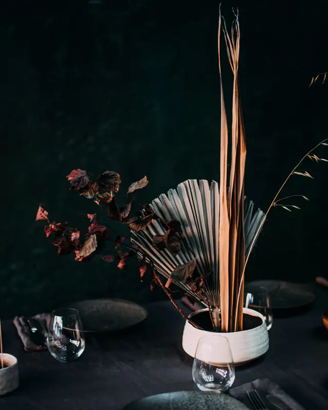 A dark dinner table with dried flowers